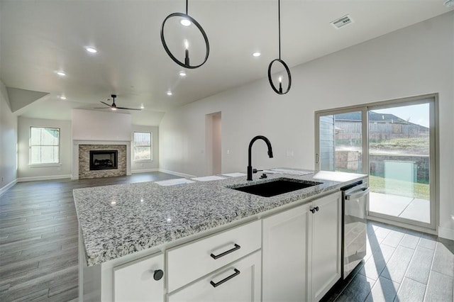 kitchen with sink, white cabinets, pendant lighting, and light hardwood / wood-style flooring