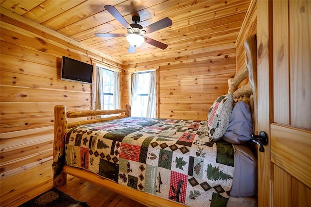 bedroom with ceiling fan, wood walls, wood-type flooring, and wood ceiling