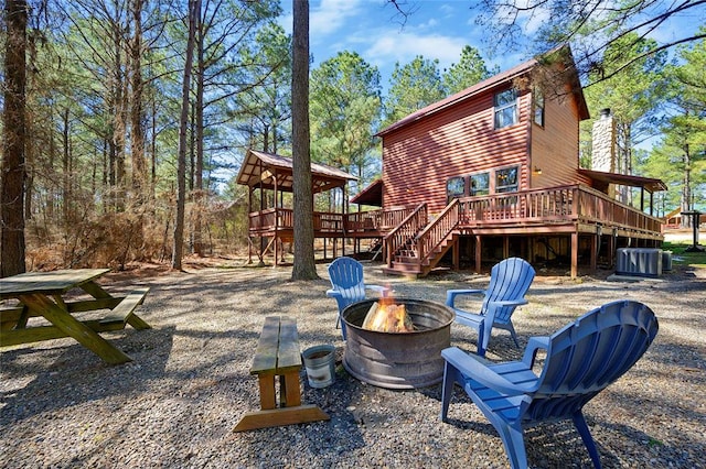 back of house featuring a deck, an outdoor fire pit, and central air condition unit