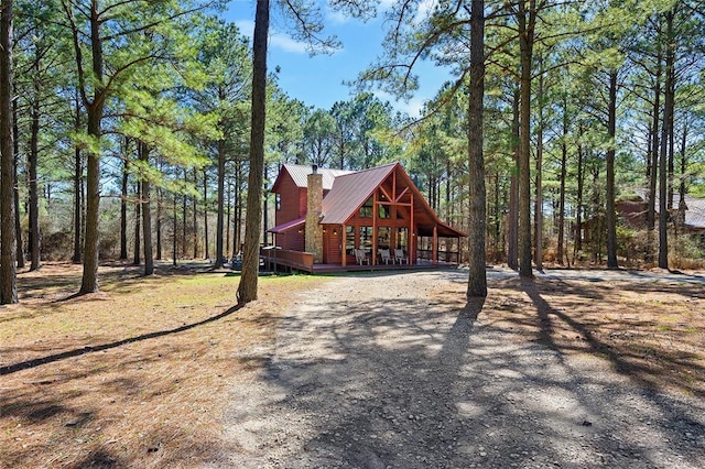 view of front of home with metal roof, a porch, and a chimney