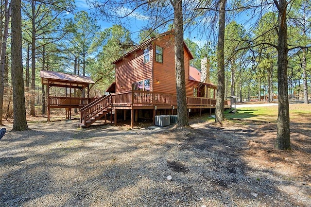 view of side of home featuring a wooden deck, stairs, central AC, and log veneer siding