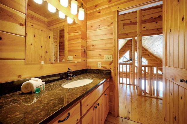 bathroom with tile patterned flooring, wood walls, and vanity