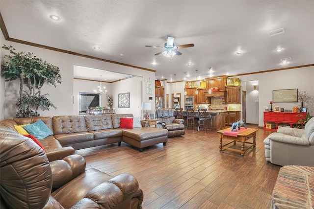 living room featuring hardwood / wood-style floors, ceiling fan with notable chandelier, and ornamental molding