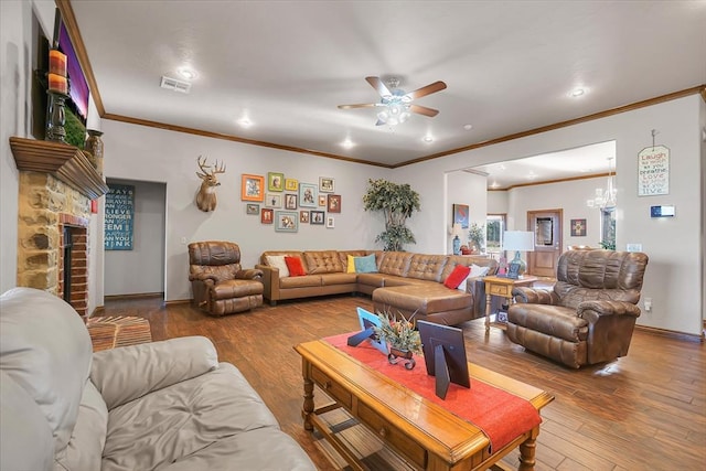 living room featuring ceiling fan with notable chandelier, a stone fireplace, wood-type flooring, and crown molding