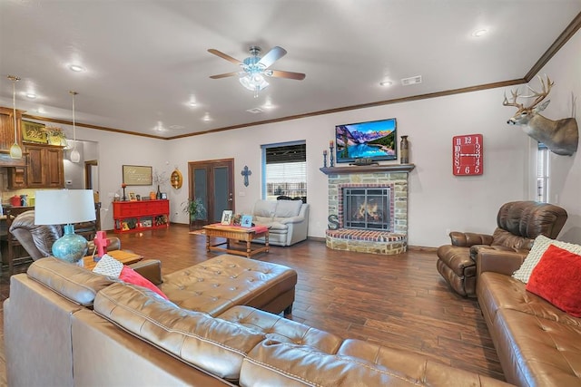 living room with a fireplace, dark hardwood / wood-style flooring, ceiling fan, and crown molding