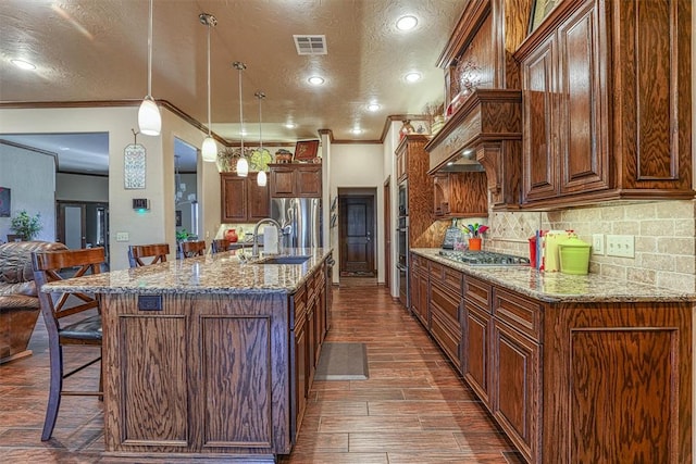 kitchen featuring a textured ceiling, a breakfast bar, ornamental molding, and hanging light fixtures