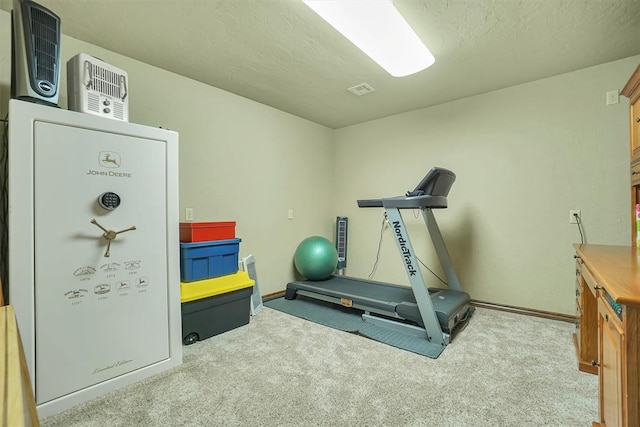 exercise area with light colored carpet and a textured ceiling