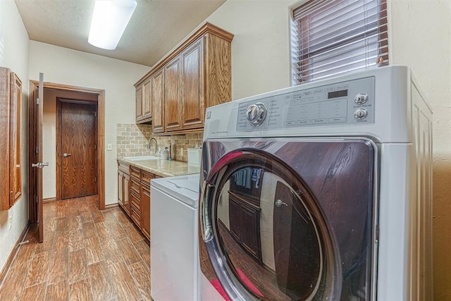 washroom featuring sink, cabinets, separate washer and dryer, dark hardwood / wood-style floors, and a textured ceiling