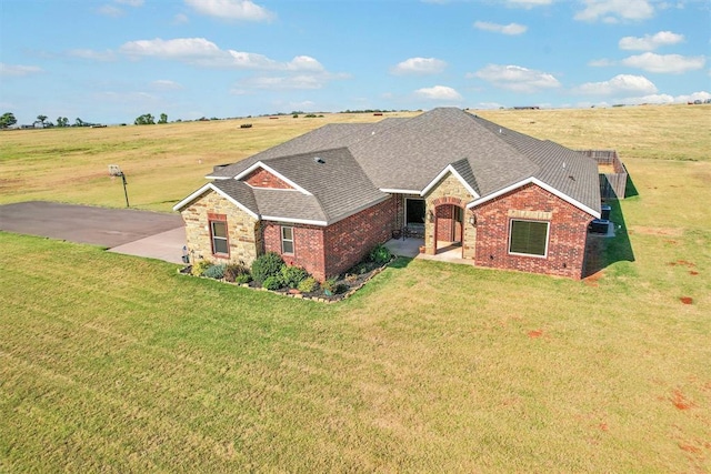 ranch-style home with a rural view and a front yard