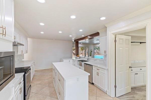 kitchen with stainless steel appliances, white cabinetry, a kitchen island, and light tile patterned floors