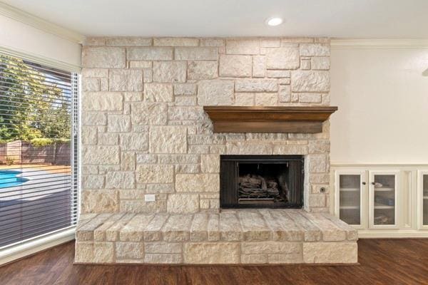 details featuring hardwood / wood-style floors, crown molding, and a stone fireplace