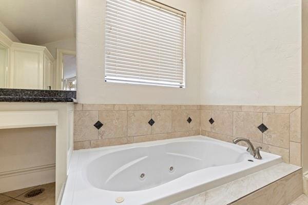 bathroom with tiled tub and tile patterned floors