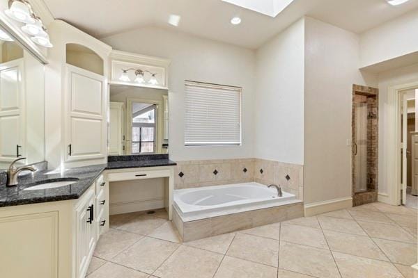 bathroom featuring tile patterned flooring, vanity, separate shower and tub, and a skylight