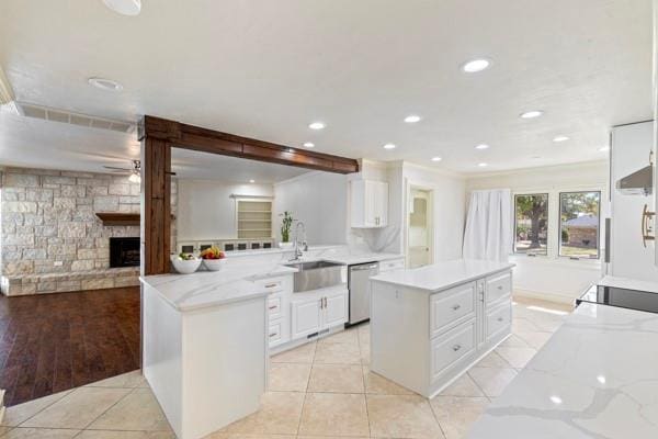 kitchen featuring light stone counters, light tile patterned floors, kitchen peninsula, dishwasher, and white cabinets