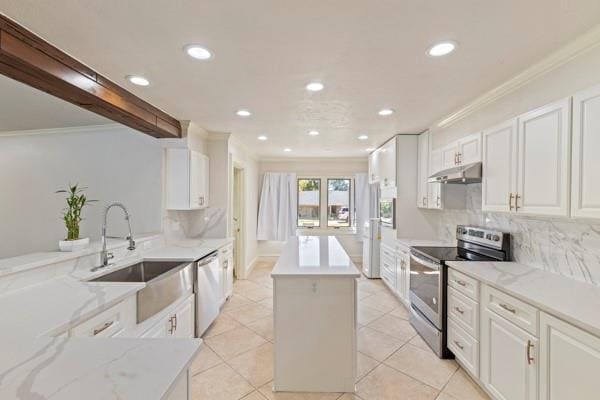 kitchen with appliances with stainless steel finishes, white cabinetry, decorative backsplash, a center island, and light stone countertops