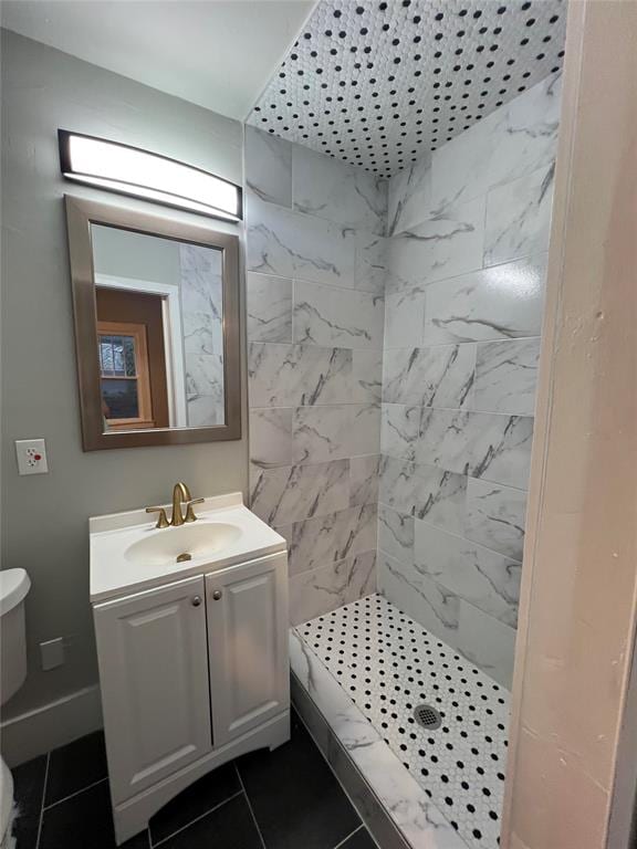 bathroom with tiled shower, vanity, toilet, and tile patterned flooring