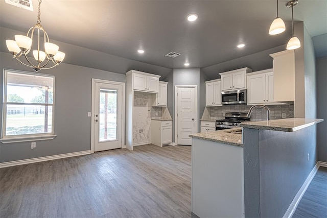 kitchen featuring white cabinetry, hanging light fixtures, stainless steel appliances, tasteful backsplash, and light wood-type flooring