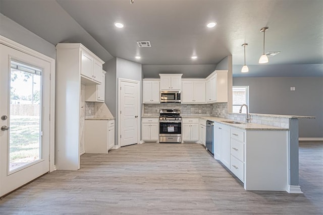 kitchen featuring white cabinetry, a wealth of natural light, stainless steel appliances, and decorative light fixtures