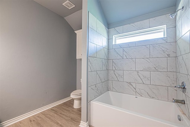 bathroom featuring toilet, wood-type flooring, lofted ceiling, and tiled shower / bath