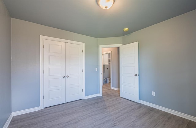 unfurnished bedroom with light wood-type flooring and a closet