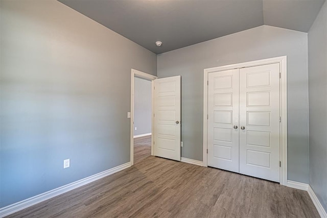 unfurnished bedroom with hardwood / wood-style floors, a closet, and lofted ceiling