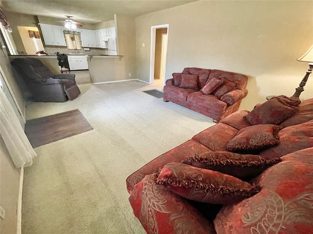 carpeted living room with ceiling fan and sink