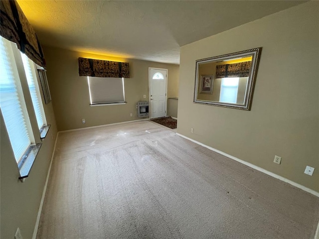 carpeted empty room with a textured ceiling and heating unit