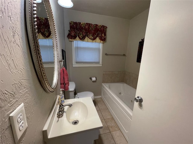 bathroom featuring tile patterned flooring, vanity, toilet, and a tub