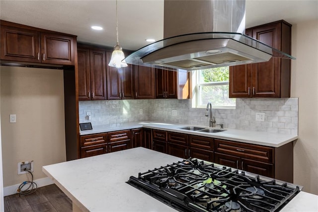 kitchen with tasteful backsplash, island range hood, sink, decorative light fixtures, and hardwood / wood-style flooring