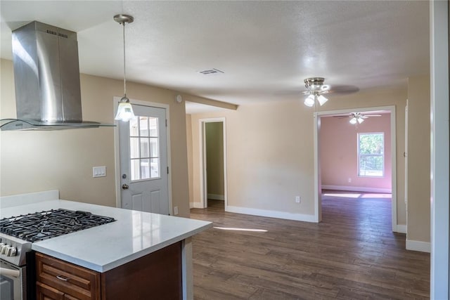 kitchen with dark hardwood / wood-style flooring, stainless steel gas range, island range hood, ceiling fan, and hanging light fixtures