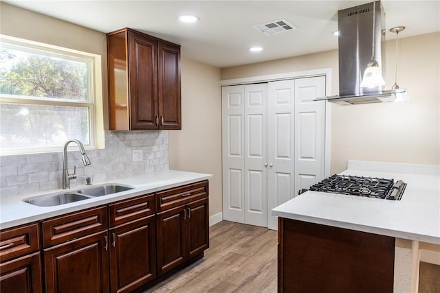 kitchen featuring pendant lighting, sink, light wood-type flooring, tasteful backsplash, and island range hood