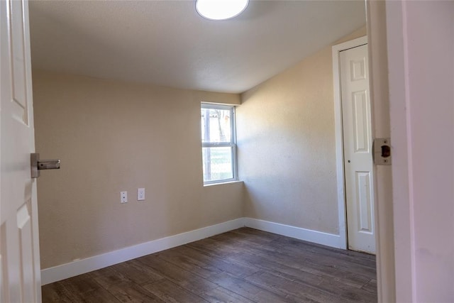 spare room with lofted ceiling and dark wood-type flooring