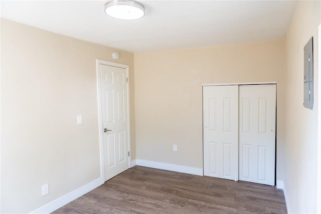 unfurnished bedroom with electric panel, hardwood / wood-style flooring, and a closet