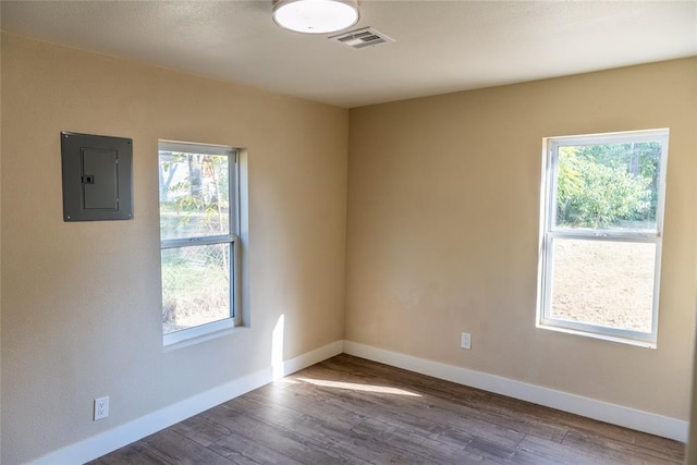 unfurnished room with electric panel and hardwood / wood-style flooring