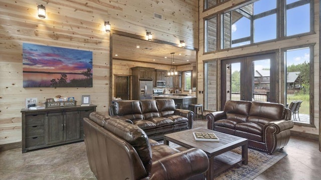 living room with wood walls, a towering ceiling, and an inviting chandelier