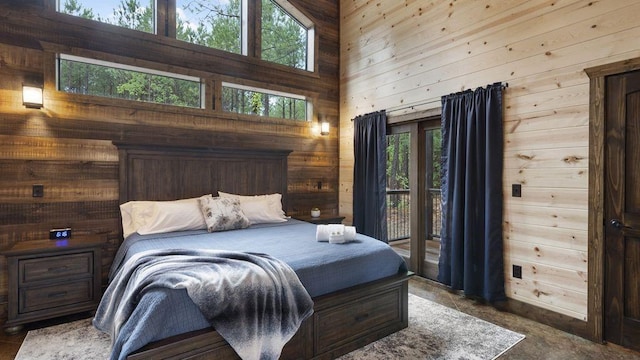 bedroom featuring wood walls, access to exterior, and a towering ceiling