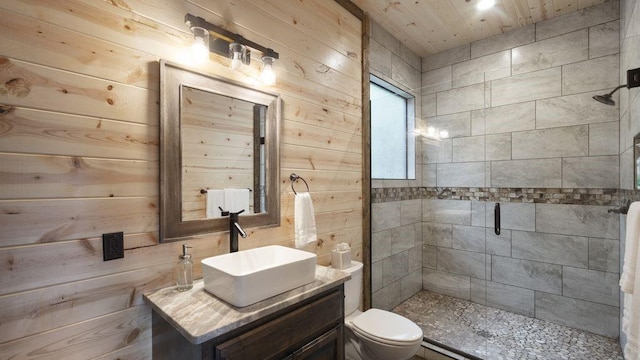 bathroom with vanity, toilet, an enclosed shower, and wooden walls