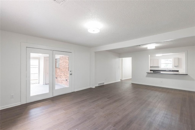 unfurnished living room featuring a textured ceiling, dark wood-type flooring, and sink