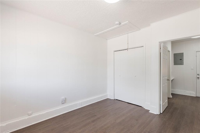 unfurnished bedroom with electric panel, a closet, dark wood-type flooring, and a textured ceiling