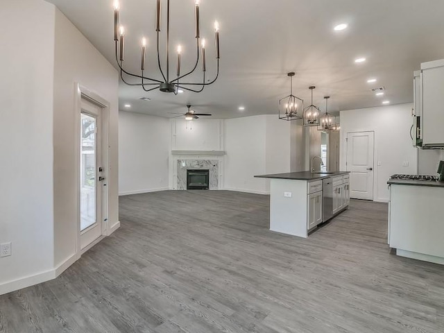 kitchen with a kitchen island with sink, a high end fireplace, hardwood / wood-style flooring, ceiling fan, and decorative light fixtures