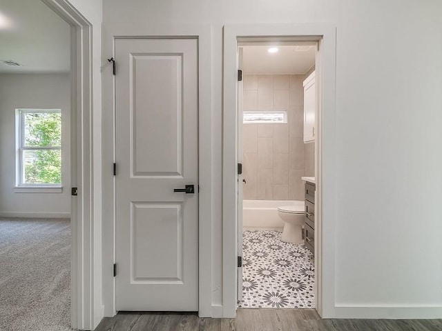 full bathroom with hardwood / wood-style flooring, tiled shower / bath combo, toilet, and vanity