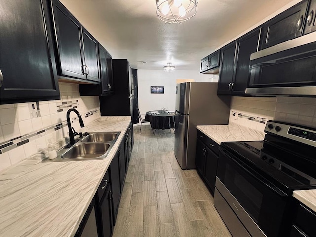 kitchen featuring light wood-type flooring, stainless steel appliances, backsplash, and sink