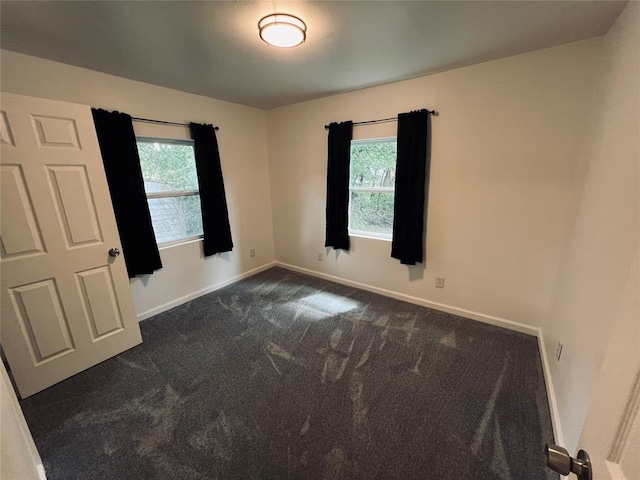 unfurnished room with a healthy amount of sunlight and dark colored carpet