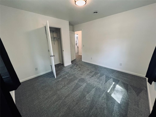 unfurnished bedroom with a closet and dark colored carpet