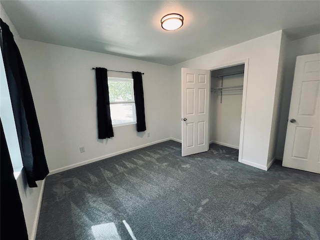 unfurnished bedroom featuring dark carpet and a closet