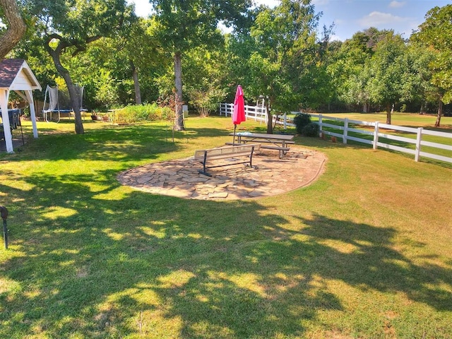 surrounding community with a lawn, a trampoline, and a patio