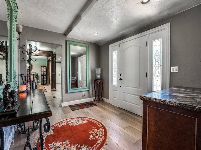 entryway with a textured ceiling and light wood-type flooring