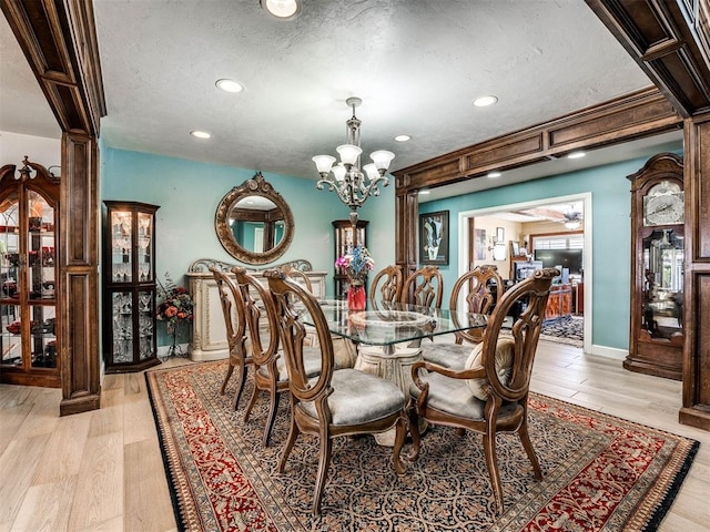 dining room featuring a textured ceiling, ceiling fan with notable chandelier, and light hardwood / wood-style floors