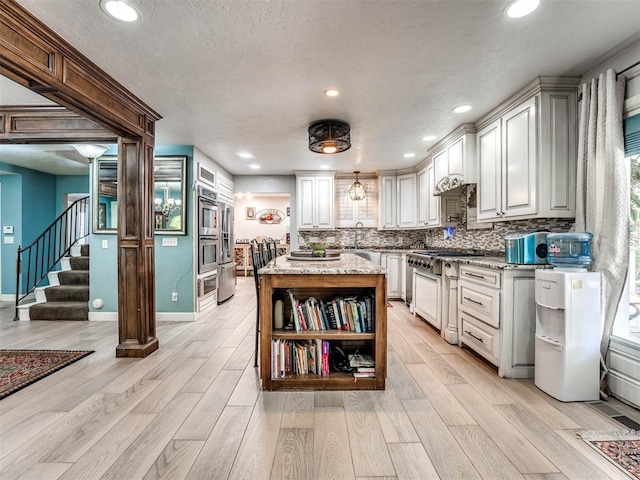 kitchen with white cabinetry, stainless steel stove, and light hardwood / wood-style flooring