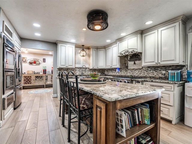 kitchen featuring light stone counters, a center island, white cabinets, and light hardwood / wood-style floors